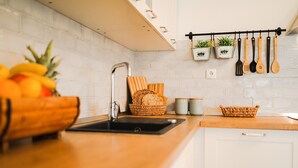 Una cocina con armarios blancos, encimera de madera, un lavamanos y un colgador para utensilios.