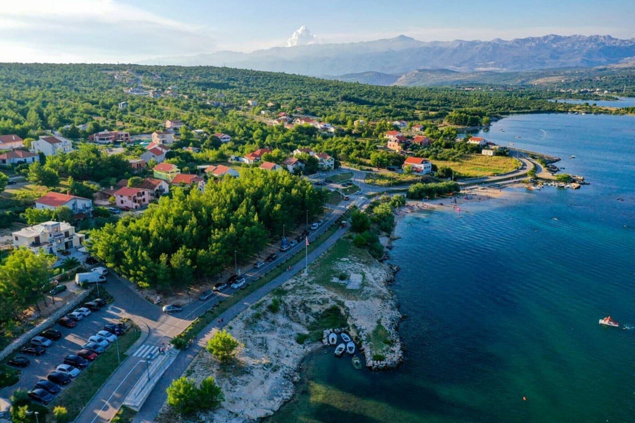 Vista aérea de un pueblo costero con casas, una carretera y un puerto deportivo.