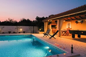A swimming pool with lounge chairs and a pool table, surrounded by a patio area with a tiled roof. - Villa in Pridraga with Private Pool (Pridraga)