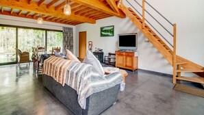 Una sala de estar moderna con un sofá grande, una escalera de madera y un comedor con sillas y una mesa.