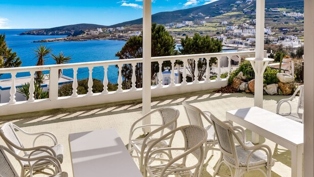 A balcony with white wicker furniture and a view of the sea and town. - Alluring Holiday Home in Syros with Barbecue (Syros)