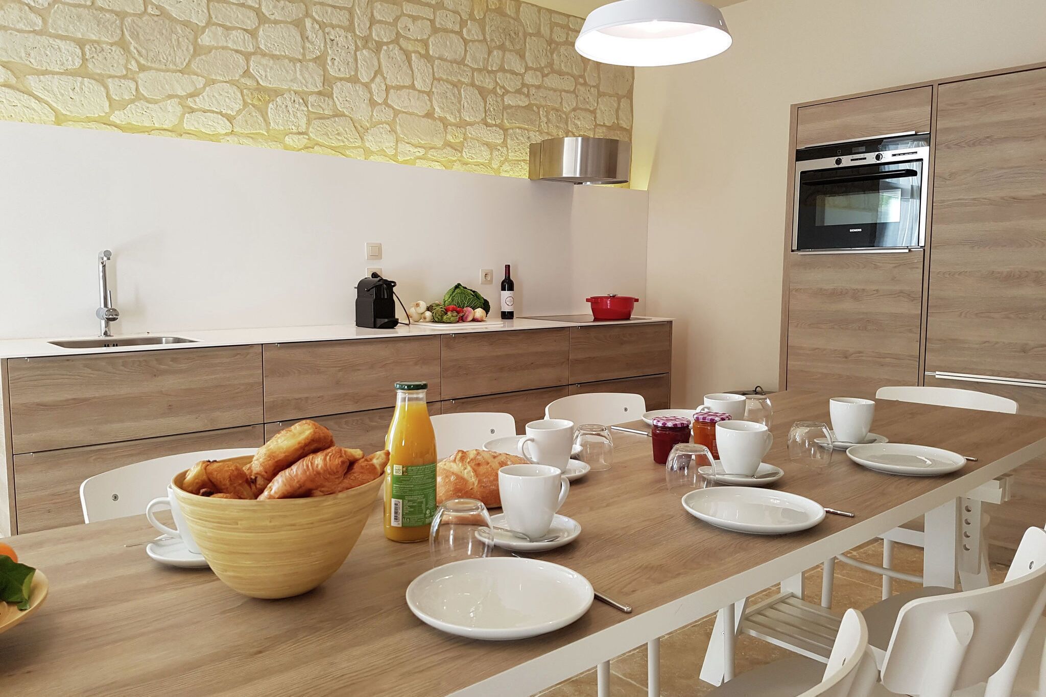 A modern kitchen with a stone backsplash, wooden cabinets, and a built-in oven.