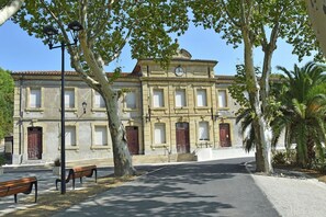 A historic building with a clock, large windows, and a central entrance. - Tranquil Stay in Villesèque (Villesèque-des-Corbières)
