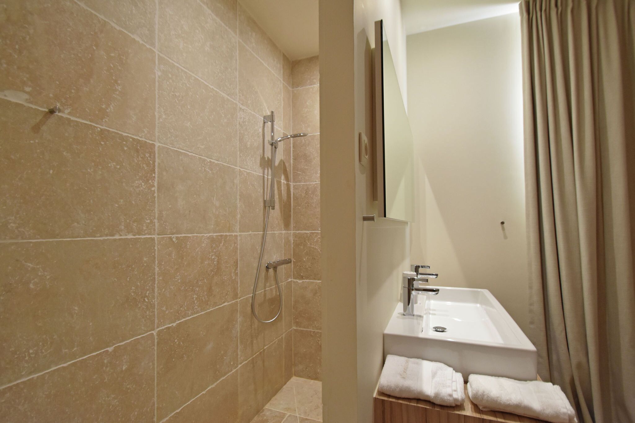 A bathroom with a shower, a sink, and a mirror.