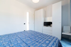A bedroom with a bed, a TV, a chair, and a wardrobe.