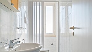 Ett modernt badrum med en stor, vit tvättställ, en toalett och en duschhörna.