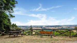 Una mesa de picnic y banco con vistas a un paisaje pintoresco, con colinas ondulantes y cielo despejado.