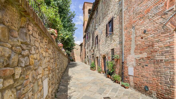 Un estrecho callejón empedrado flanqueado por edificios históricos con muros de ladrillo y pequeñas ventanas.