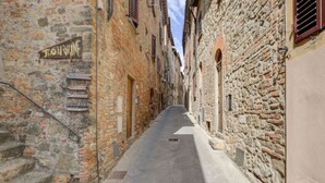 Un estrecho callejón empedrado con un letrero de "Jhonwine" y otros indicadores de comercios locales.