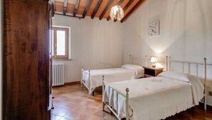 Un dormitorio con dos camas individuales, un armario de madera, un radiador y una ventana.
