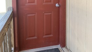 Une porte rouge avec une enseigne indiquant « Escudido » et une poignée de porte en métal.