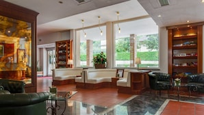 A spacious lobby with a reception desk, seating area, and a large window offering a view of greenery. - Family escape with Pools and Sauna (Foligno)