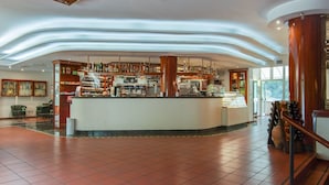 A bar area with a curved counter, shelves of bottles, and a coffee machine. - Family escape with Pools and Sauna (Foligno)