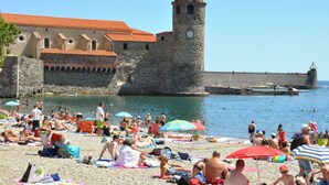 A crowded beach with people sunbathing and swimming, a historic stone building with a tower, and a clear blue sky. - Blissful Stay in Mandourelle (Villesèque-des-Corbières)
