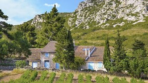 A rustic stone building with a tiled roof, surrounded by vineyards and a mountainous backdrop. - Blissful Stay in Mandourelle (Villesèque-des-Corbières)