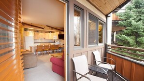 A modern kitchen with wooden cabinets and a dining area with a red sofa and white chairs. - Laurelwood, A Destination Residence (Snowmass Village)