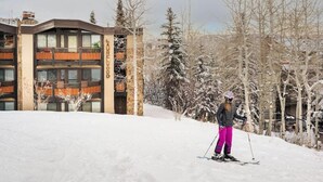 A ski resort building with a ski slope in the foreground. - Laurelwood, A Destination Residence (Snowmass Village)