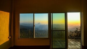 A room with a large window overlooking a mountainous landscape during sunset. - XALAKHAM PHOUKHOUN - Campsite (Phou Khoun)