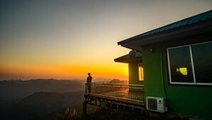 A person standing on a balcony overlooking a sunset. - XALAKHAM PHOUKHOUN - Campsite (Phou Khoun)