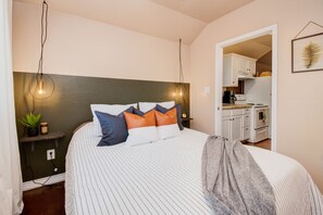 A bedroom with a bed, pillows, bedside table, and a hanging light fixture. - ⫷1 BD/1 Bath⫷Tiny Magnolia Retreat⫷⫸Near TTU⫸ (Lubbock)