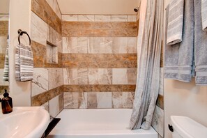 A bathroom with a bathtub, a sink, and a shower area with a tiled wall. - ⫷1 BD/1 Bath⫷Tiny Magnolia Retreat⫷⫸Near TTU⫸ (Lubbock)