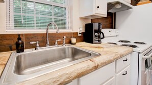 A kitchen with a stainless steel sink, a coffee maker, and a stove. - ⫷1 BD/1 Bath⫷Tiny Magnolia Retreat⫷⫸Near TTU⫸ (Lubbock)