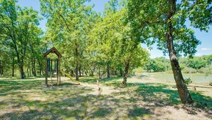 A park with a wooden play structure and a pond.