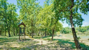Un parque con una estructura de juego de madera y un lago al fondo.