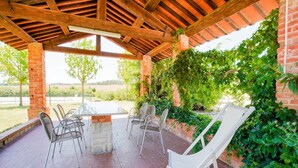 Un patio cubierto con pared de ladrillo, una mesa y sillas.