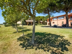 Il s’agit d’une propriété résidentielle dotée d’une pelouse bien entretenue, de plusieurs arbres et d’une maison avec un toit en tuiles et une façade en briques.