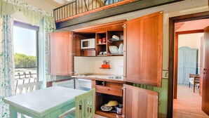 A compact kitchen with wooden cabinets, a microwave, and a sink.