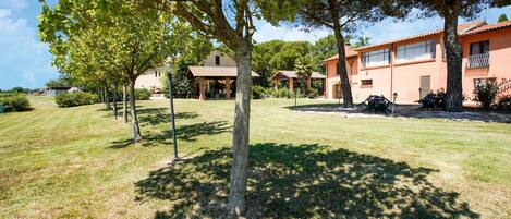 A property with a well-maintained lawn, multiple trees, and a building with a tiled roof.