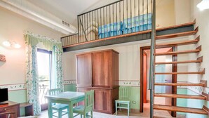 A cozy room with a wooden staircase, a dining table with chairs, and a small table with a chair.