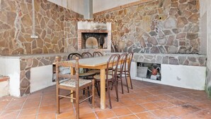 A stone-clad outdoor dining area with a built-in brick oven, wooden table, and chairs. - Apartment in Agropoli with garden (Agropoli)