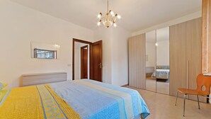 A bedroom with a bed, a chair, a wardrobe, and a mirror. - Apartment in Agropoli with garden (Agropoli)