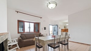 A dining area with a table and chairs, a sofa, a fireplace, and a kitchen in the background. - Apartment in Agropoli with garden (Agropoli)