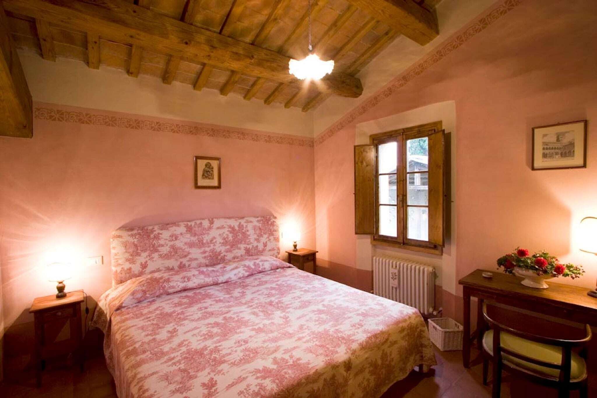 A bedroom with a bed, a desk, a chair, a radiator, and a window.
