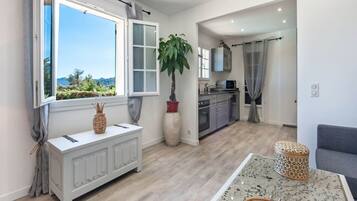 Un salon moderne avec une console blanche, une grande plante en pot et une vue sur l’extérieur.