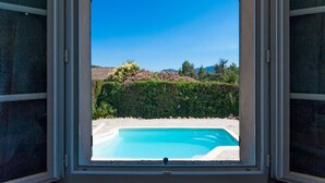 A clear view of a swimming pool through a window, surrounded by greenery and a clear blue sky. - Riviera Hideaway for 2 Guests (La Roquette-sur-Siagne)