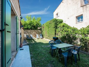A patio with a table and chairs, a barbecue grill, and a green door.