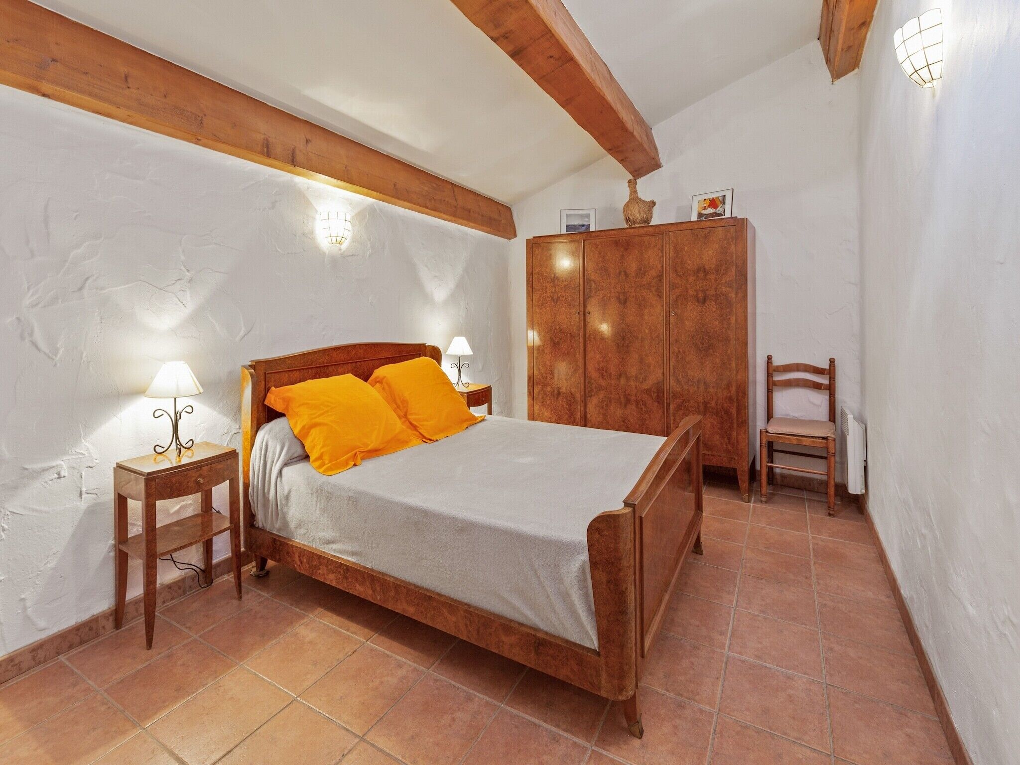 A bedroom with a wooden bed, two nightstands, a wardrobe, and a chair.