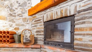 Un muro de piedra con una chimenea, una cesta de mimbre y tuberías de terracota.