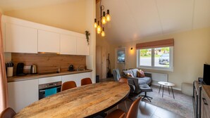 Una cucina moderna con mobili bianchi, un piano di lavoro in legno e un'area pranzo con un tavolo in legno e sedie arancioni.