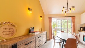 Una cucina moderna con zona pranzo, un mobiletto in legno con cassetti, un cartello di benvenuto e un lampadario.