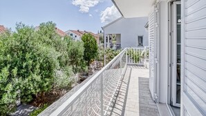 A balcony with a white railing overlooking a garden and neighboring houses. - Villa in Orebić near Sea Beach (Orebić)