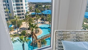 Ein Hotelzimmer mit Blick auf ein Resort-Schwimmbad, inklusive Wasserrutsche und Palmen.