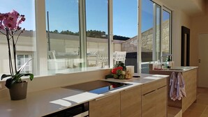 A modern kitchen with large windows, a central island, and a view of the outdoors. - Serene Family Escape (Villesèque-des-Corbières)