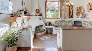 A cozy living room with a fireplace, a large window with curtains, a bookshelf, and a TV.