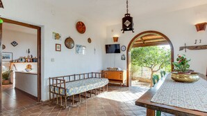 A dining area with a long wooden table, a bench, and a view of the outdoors.