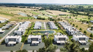 A residential area with modern white houses arranged in a grid pattern, surrounded by green fields and a golf course. - Classy Holiday Home in Lutzmannsburg (Zsira)